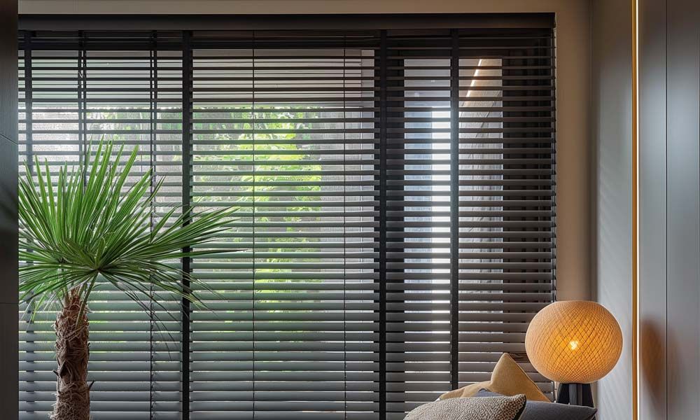 Black Venetian blinds filtering light into a cozy room with modern decor.