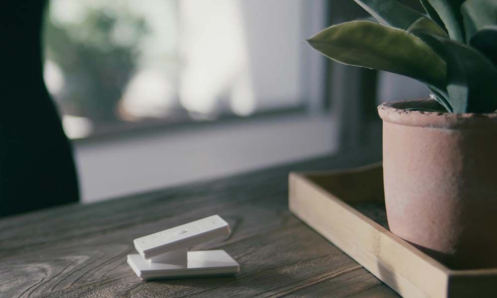 A wooden table with remote controls next to a plant, highlighting convenient shading control.