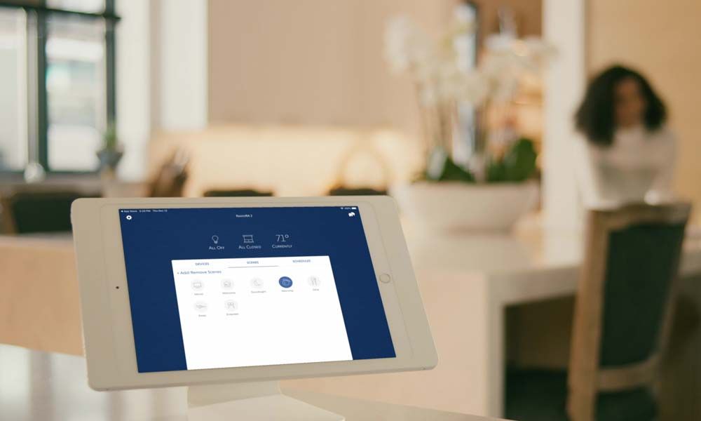 A smart home touch panel displaying shading controls on a modern tabletop.